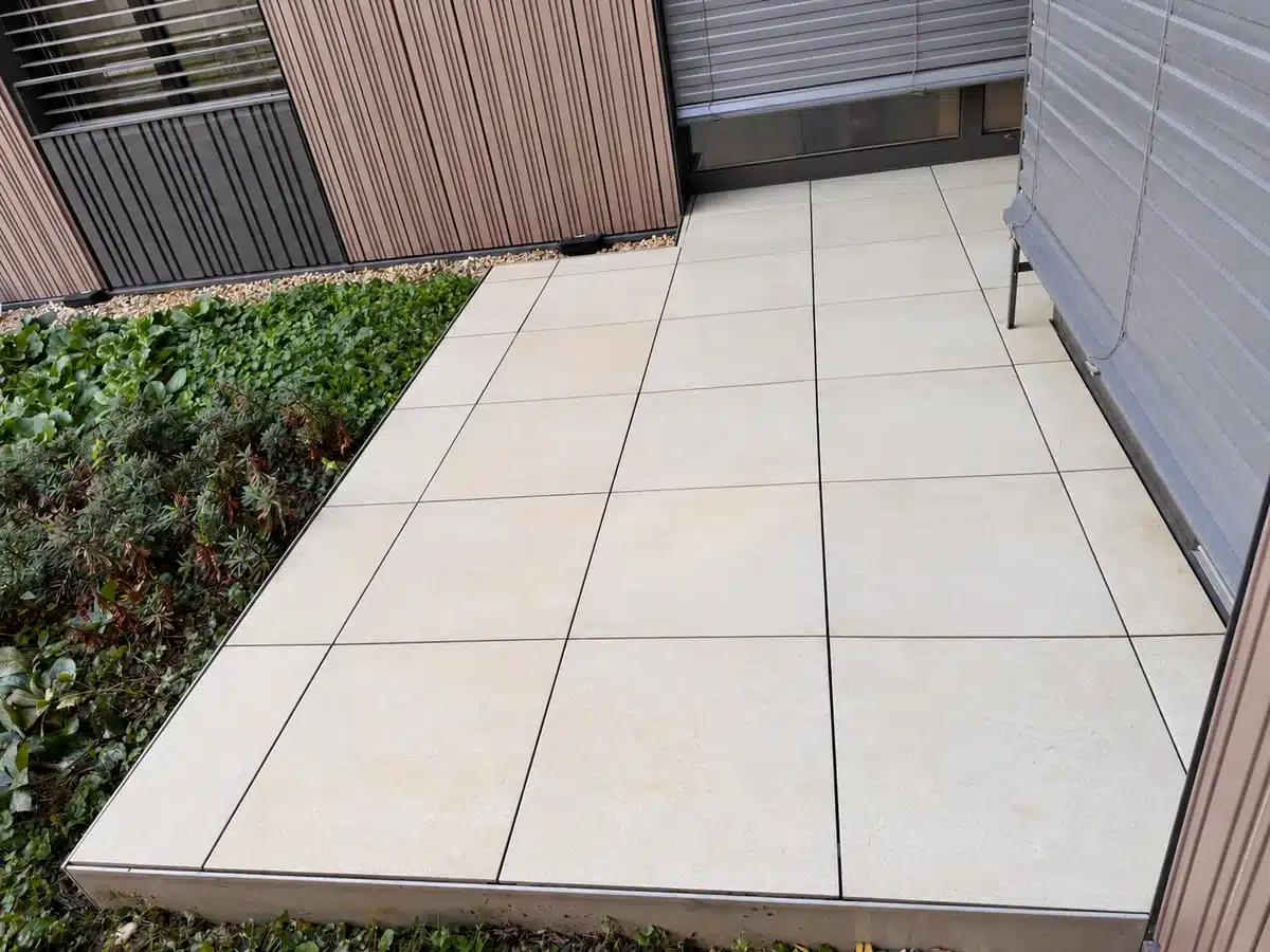 Terrasse en dalles après nettoyage, le long d’un massif végétalisé.